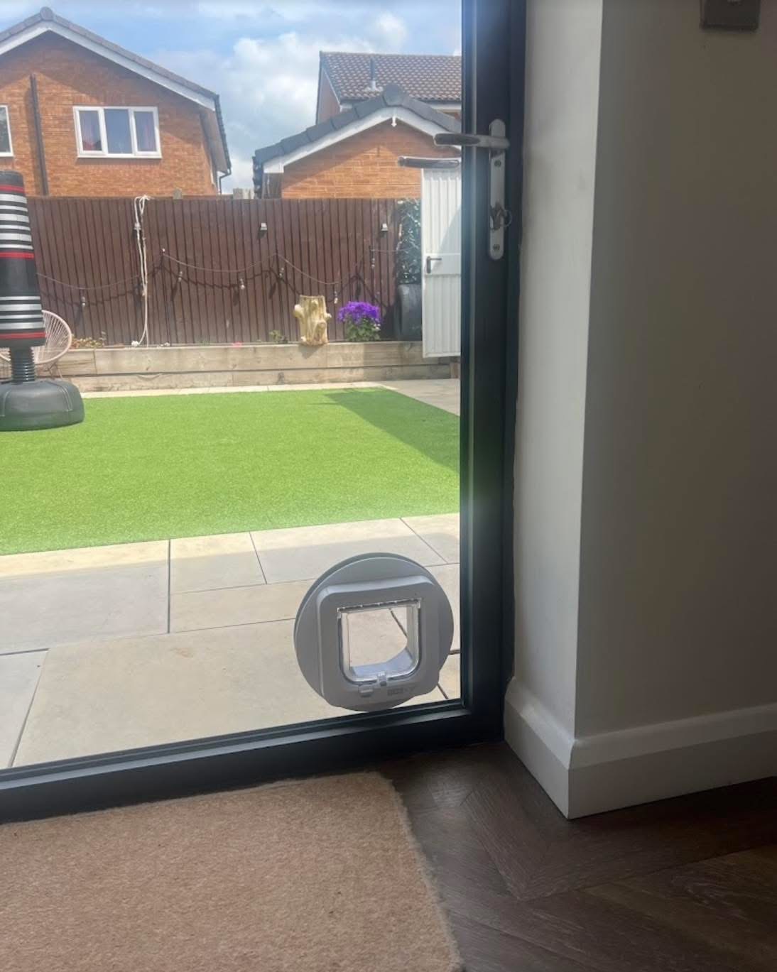 Grey round cat flap fitted into a new toughened glass panel in an anthracite bi-fold door