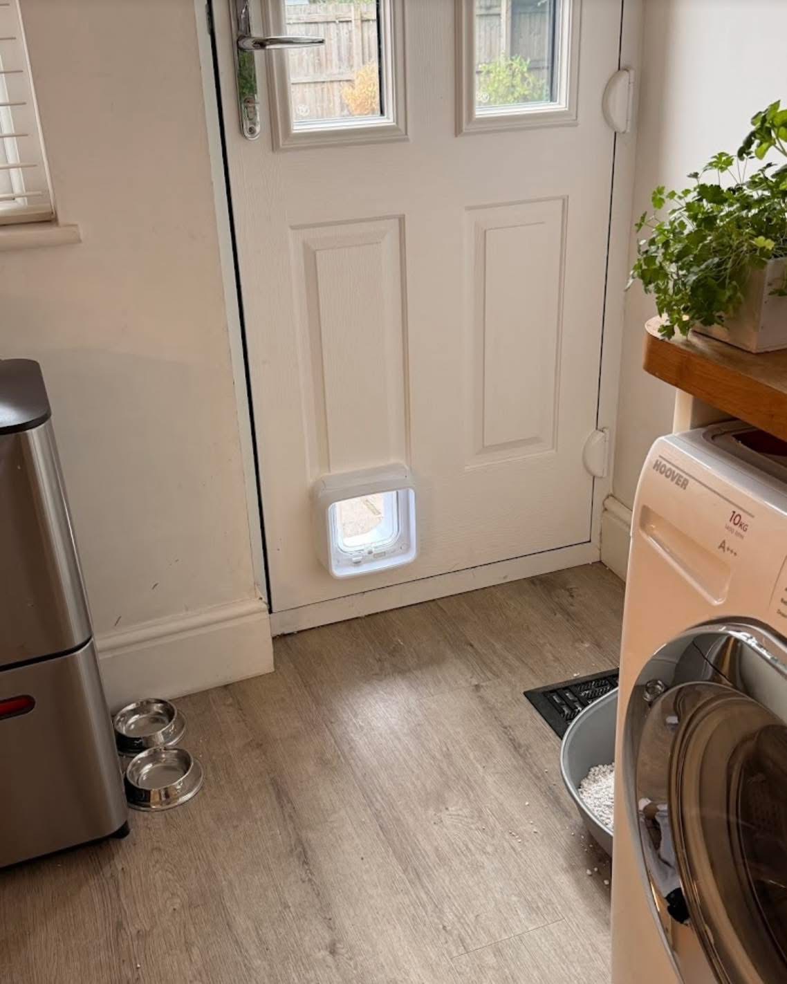 Microchip cat flap fitted in a white composite back door in a kitchen utility area by professional installer