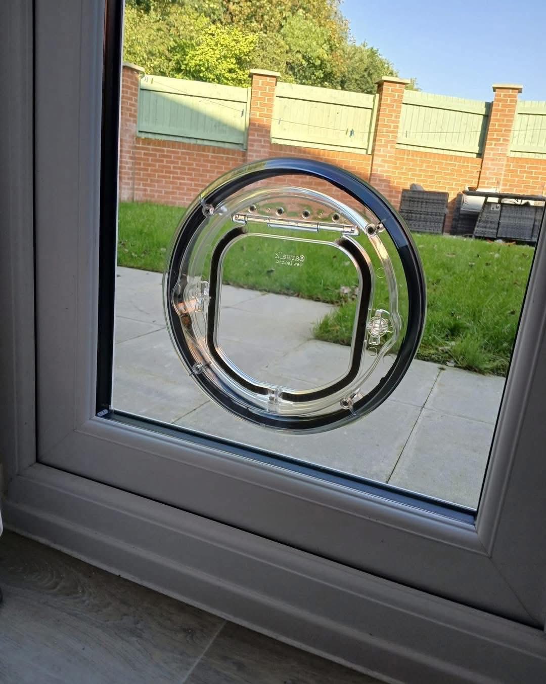 Cat flap in a glass door panel on a sunny day with garden view